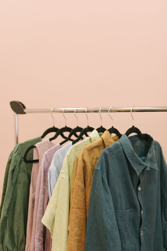 Stylish assortment of colorful linen shirts hanging on a rack against a neutral background.